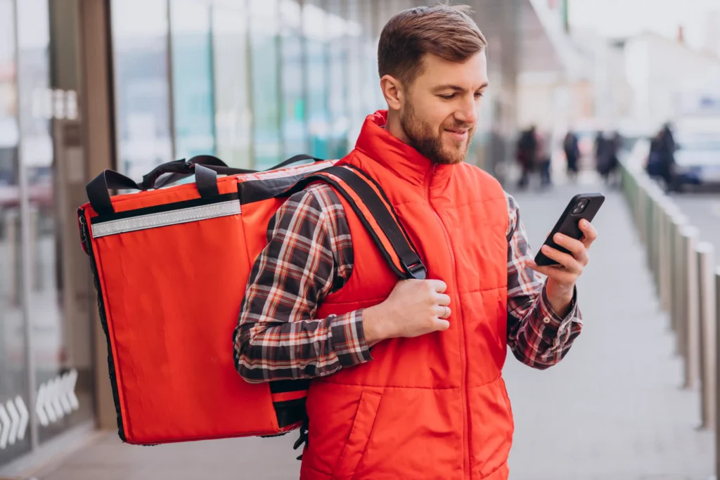 Entregador olha celular para ilustrar conteúdo sobre aposentadoria de motorista de aplicativo