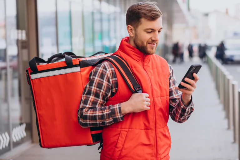 Entregador olha celular para ilustrar conteúdo sobre aposentadoria de motorista de aplicativo